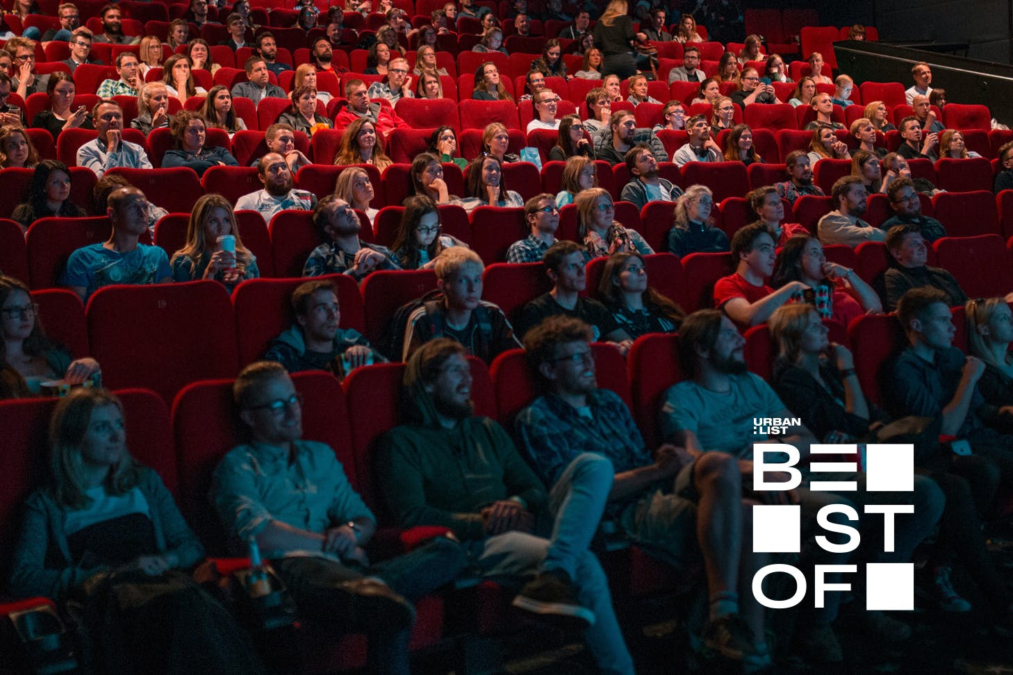 People have a good time at the cinema, sitting in plush red seats.